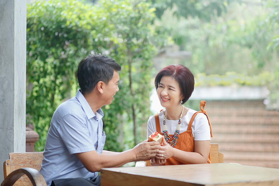 Asian middle-aged man gives a present to his wife in anniversary wedding day Photograph by Toa55