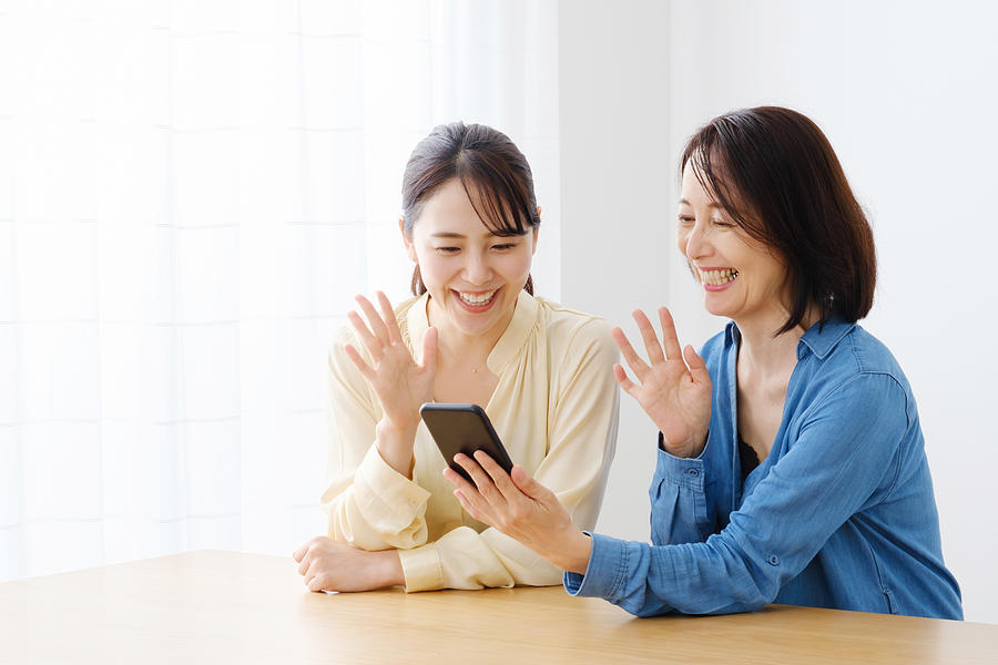 Asian Mother And Daughter Using Smart Phone At Living Room Photograph by Itakayuki