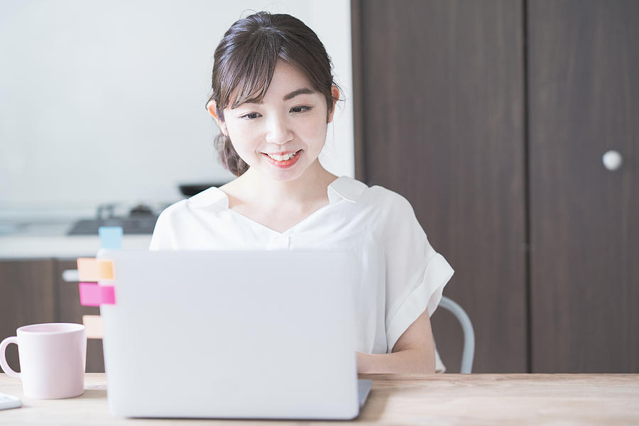Asian woman doing remote work with laptop Photograph by Maruco