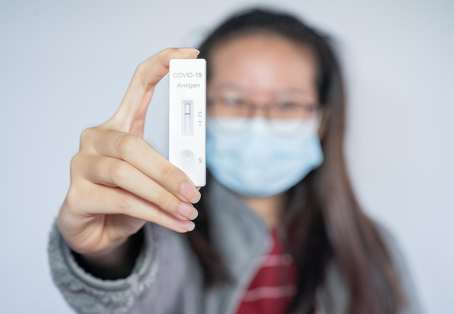 Asian woman holding a rapid antigen test pad after testing result is negative. Photograph by Boy_Anupong