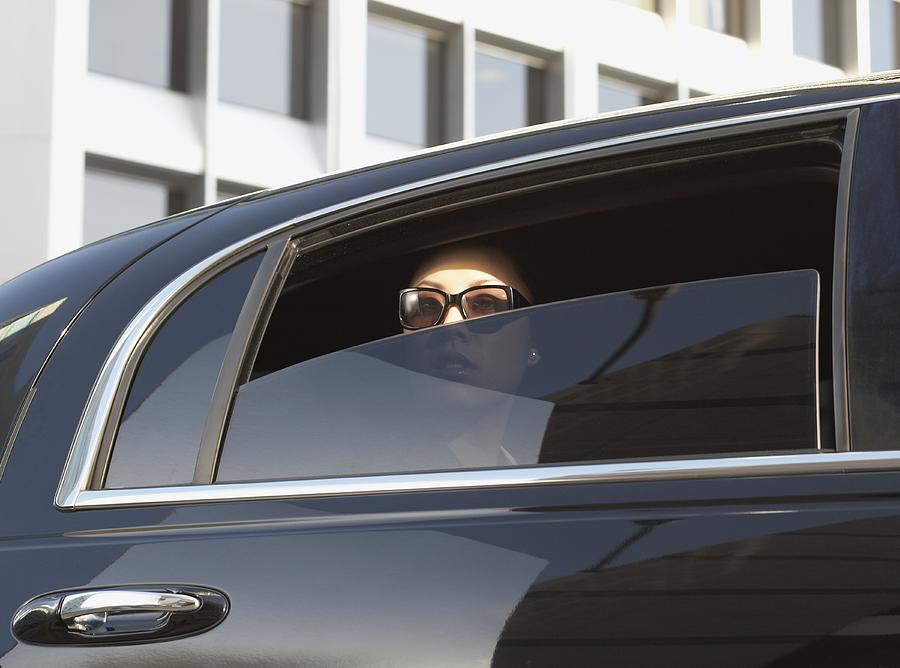 Asian woman in limousine with window part of the way down Photograph by Kris Timken
