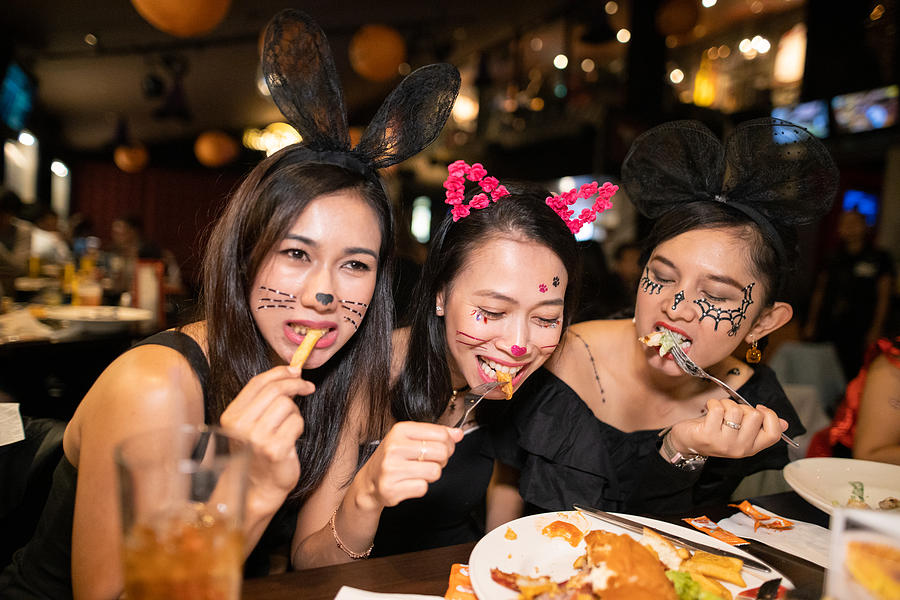 Asian women in halloween costume eating dinner at restaurant together Photograph by Satoshi-K