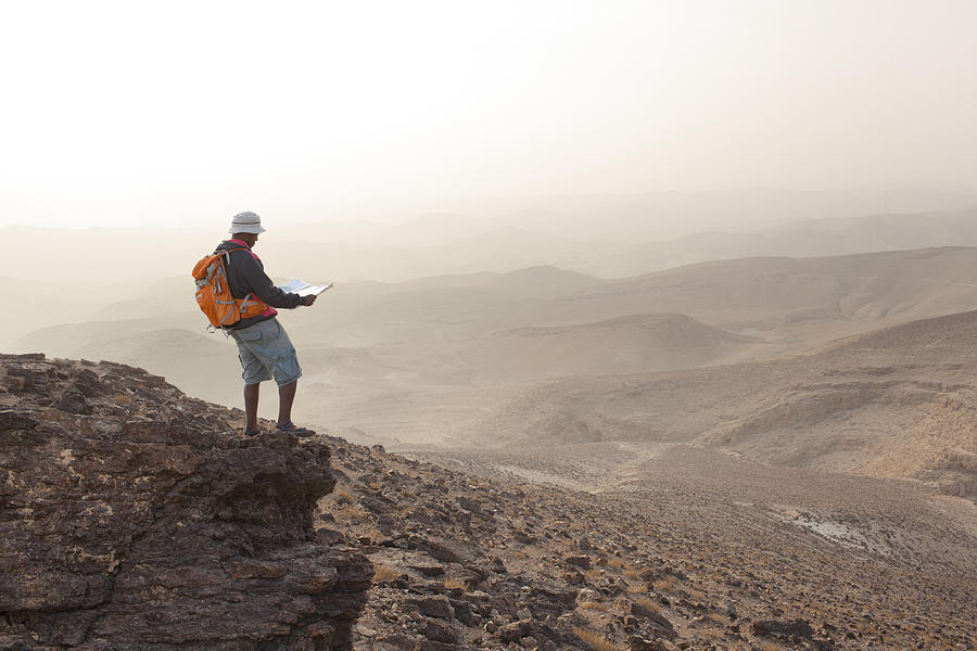 Aspirations for adventure. Reading map and looking on horizon over desert landscape. Photograph by RuslanDashinsky