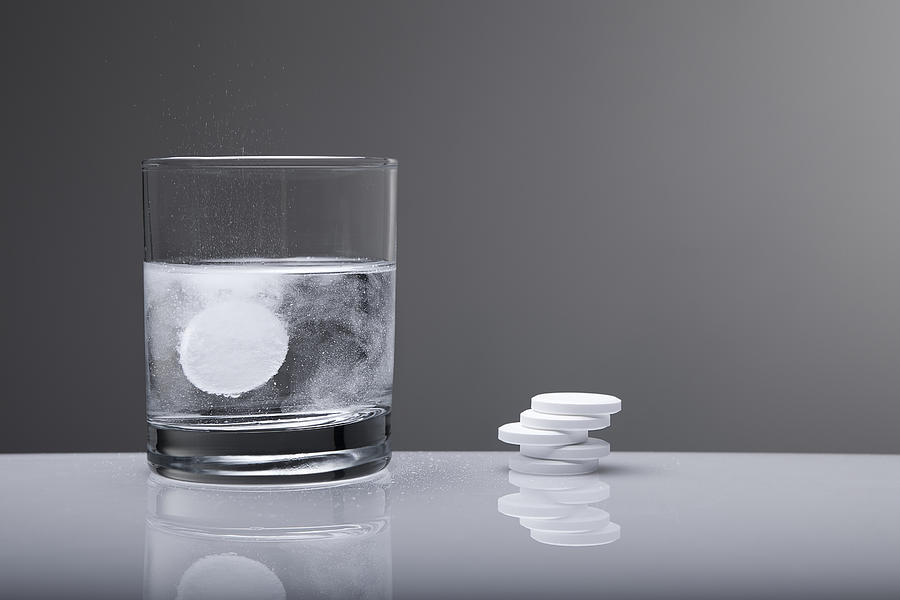 Aspirin paracetamol pill splashing into glass of water Photograph by Ilbusca