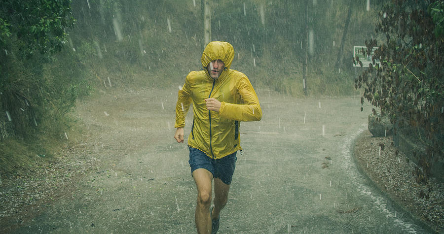 Athletic man jogging in extreme weather condition. Hail and rain Photograph by Janiecbros