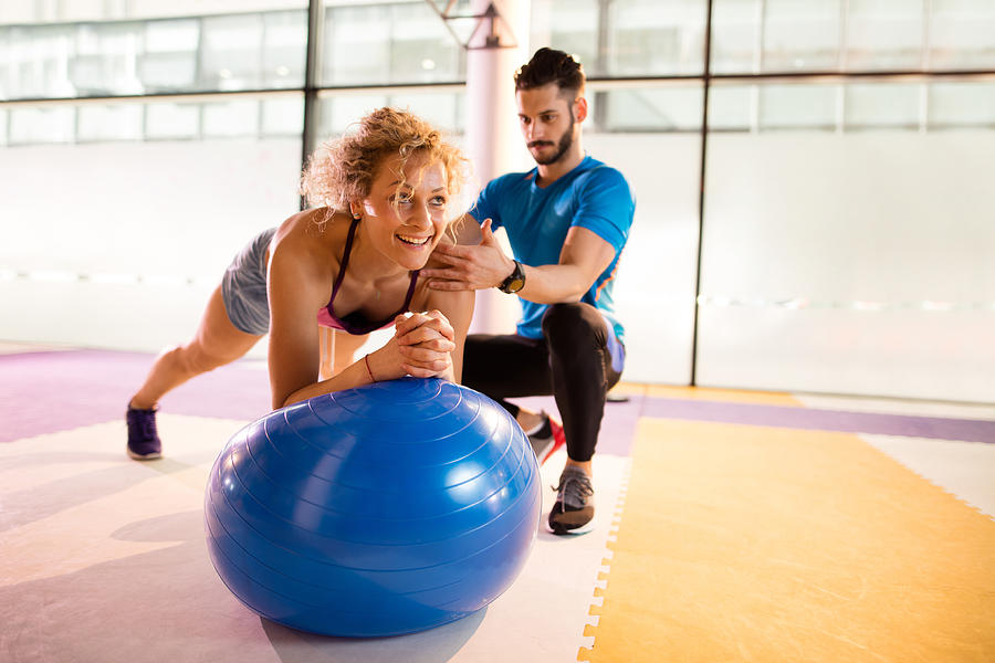 Athletic woman having Pilates training with fitness instructor. Photograph by Skynesher