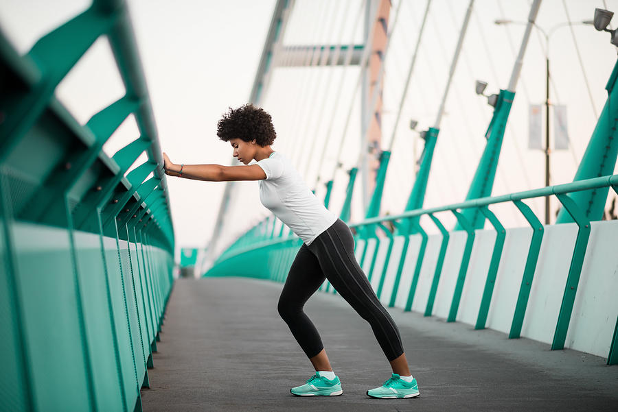 Athletic, young woman exercising on city bridge Photograph by Martin Novak