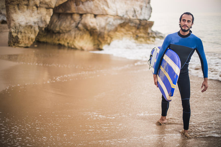 Attractive man carrying surfboard at the beach Photograph by South_agency