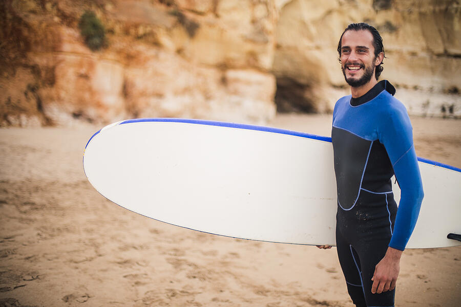 Attractive man carrying surfboard Photograph by South_agency