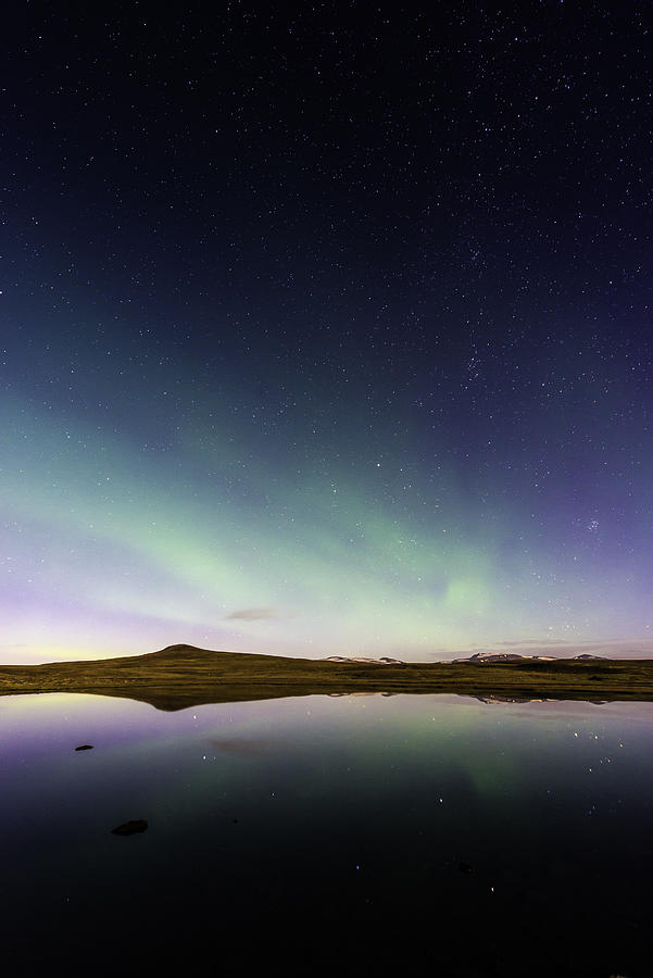 Aurora and glittering stars reflecting in tranquil mountain lake Iceland Photograph by fotoVoyager