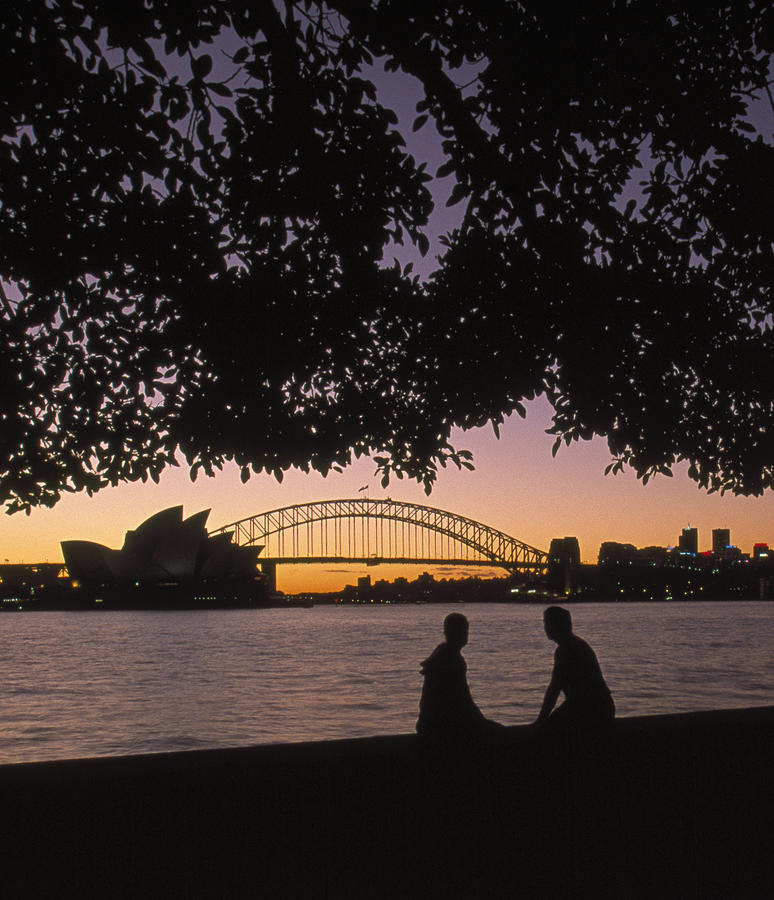 Australia, New South Wales, Sydney, silhouette of couple with Harbour Bridge and Opera house in background at sunset Photograph by Grant Faint
