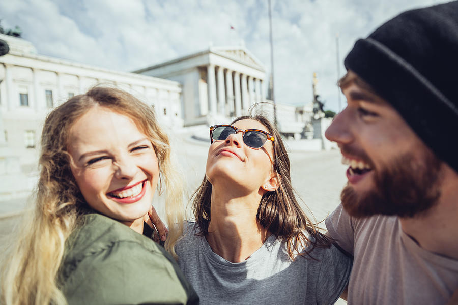 Austria, Vienna, three friends having fun in front of the parliament building Photograph by Westend61