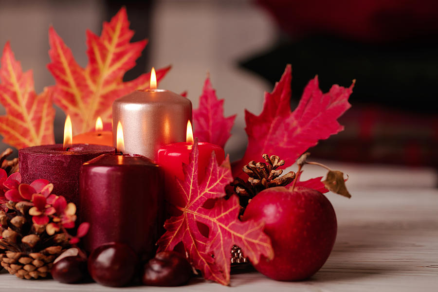 Autumn still life - candles, leaves and cones on the background of pillows. Photograph by Oleh_photographer