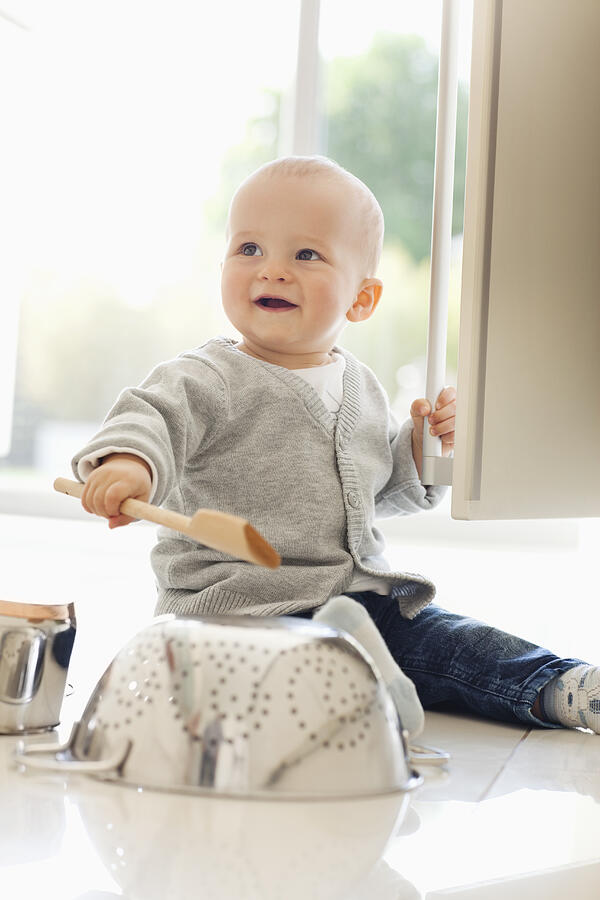 Baby banging on colander with wooden spoon Photograph by Sam Edwards