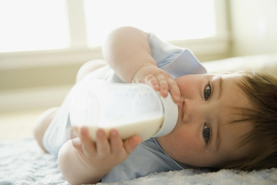 Baby boy drinking milk from milk bottle Photograph by Paul Burns