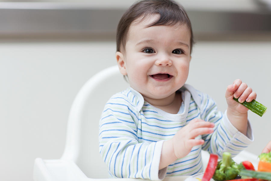 Baby boy eating healthy vegetables Photograph by Image Source