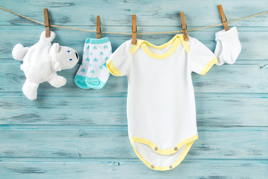 Baby clothes, onesie, socks, white bear toy on a clothesline Photograph by Dash_med