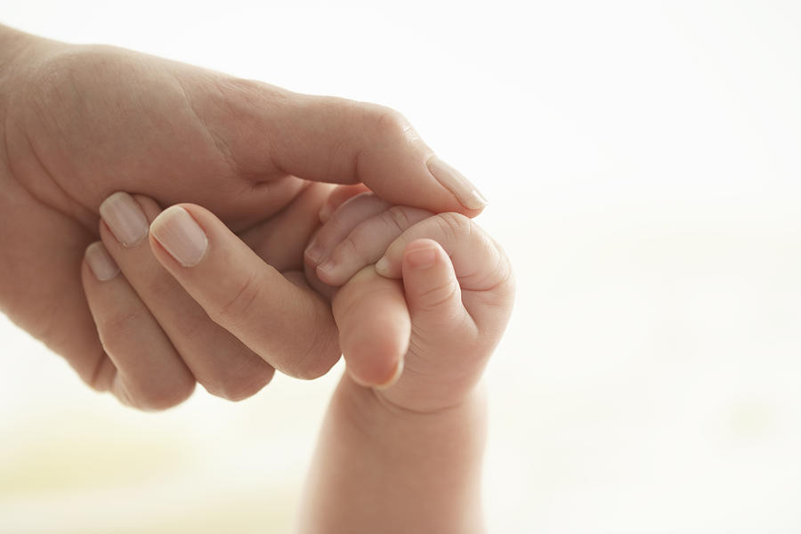 Baby girl (3-6 months) holding womans hand, close-up Photograph by Marili Forastieri