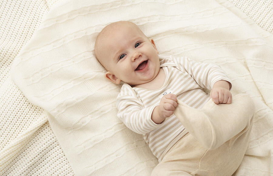 Baby girl (3-6 months) lying on blanket, smiling Photograph by Marc Debnam