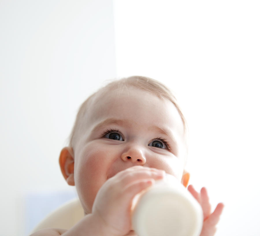 Baby girl (9-12 months) drinking from bottle. Photograph by Steven Errico