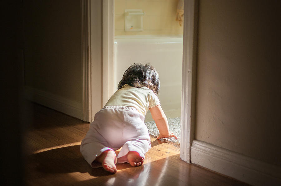 Baby girl crawling through passage in home Photograph by Bradleyhebdon