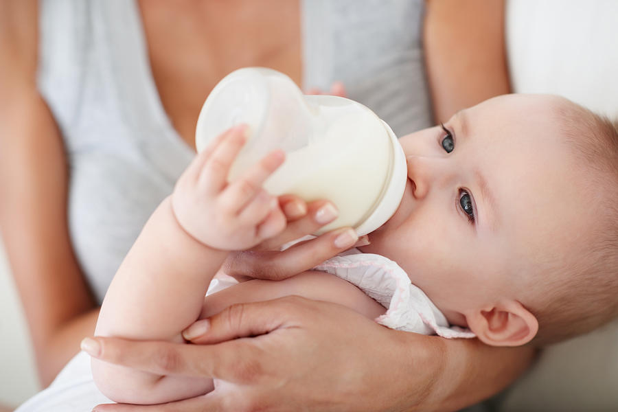 Baby girl drinking milk from bottle Photograph by Kupicoo