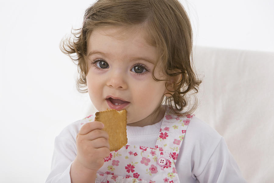 Baby girl eating cookie, close up Photograph by Westend61