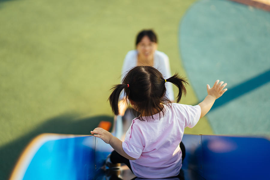 Baby girl playing on slide in playground Photograph by Insung Jeon