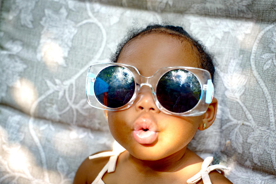Baby girl sitting on lounge chair wearing sunglasses, portrait Photograph by Sue Barr