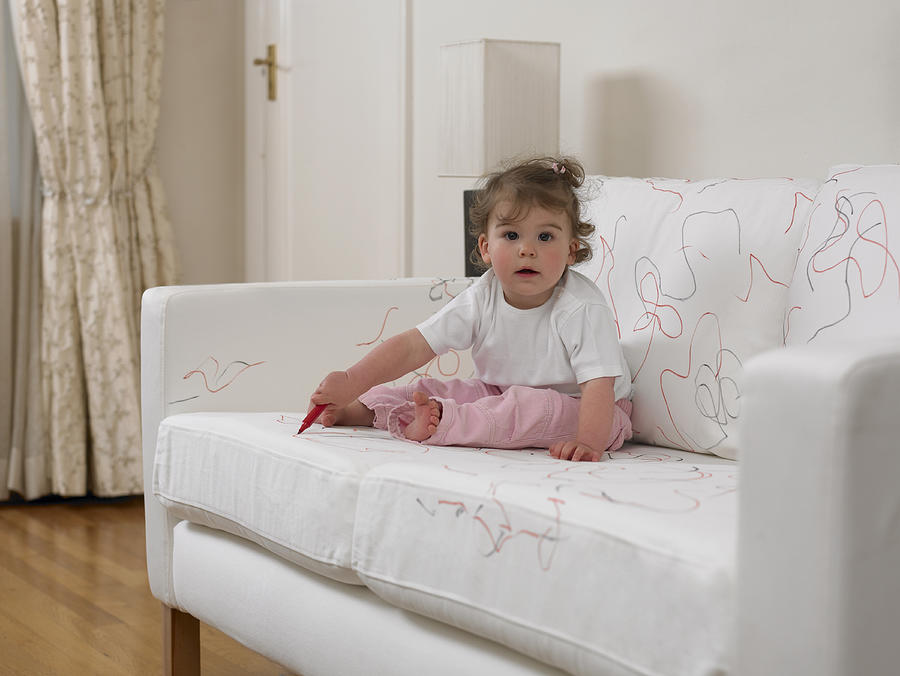 Baby girl using marker on sofa Photograph by Adam Gault