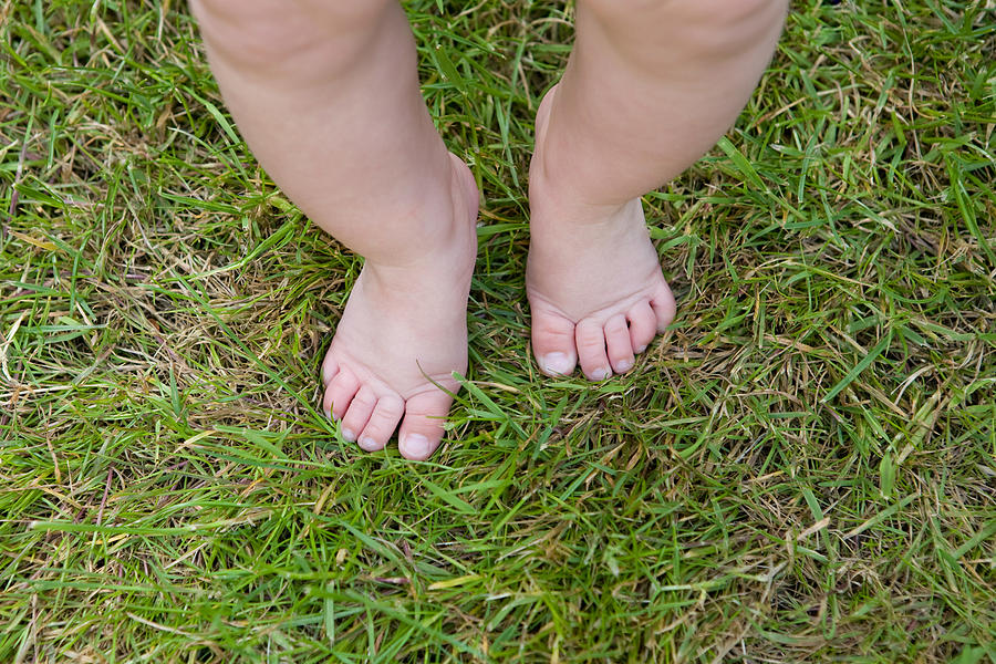 Baby legs and feet on grass Photograph by Image Source