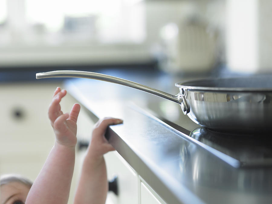 Baby reaching for hot frying pan on stove Photograph by Adam Gault