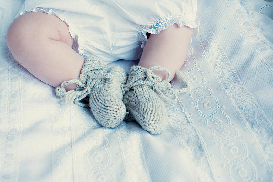 Baby with knitted booties, low section Photograph by PhotoAlto/Anne-Sophie Bost