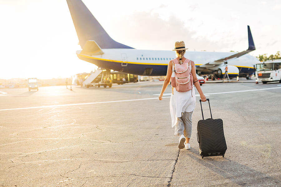 Back view of a woman walking towards the plane, ready to board and begin her vacation Photograph by Kosamtu