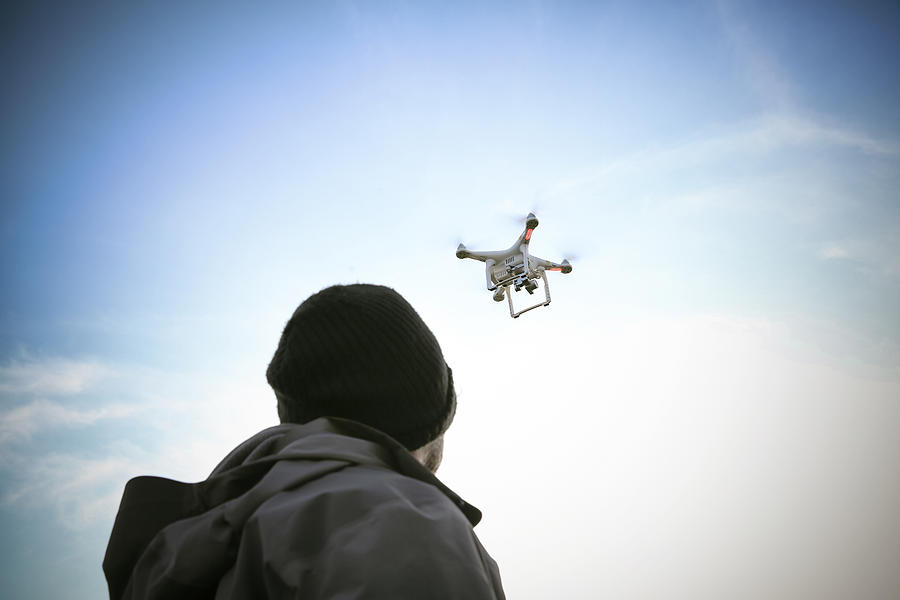 Back view of man flying drone Photograph by Westend61