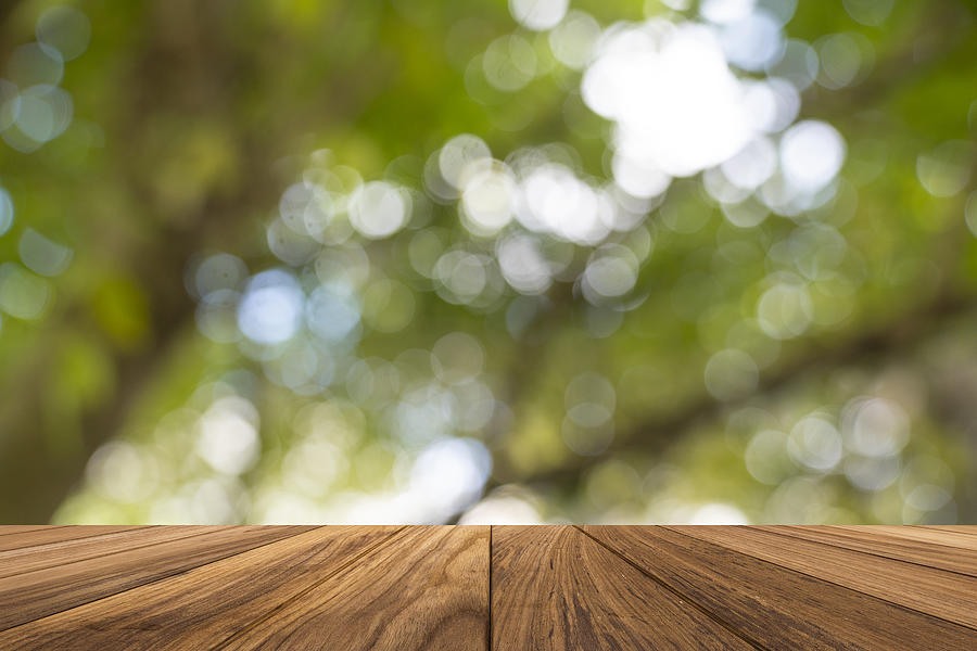 Backgrounds: Empty wooden table with defocused green lush foliage at background Photograph by Witthaya Prasongsin