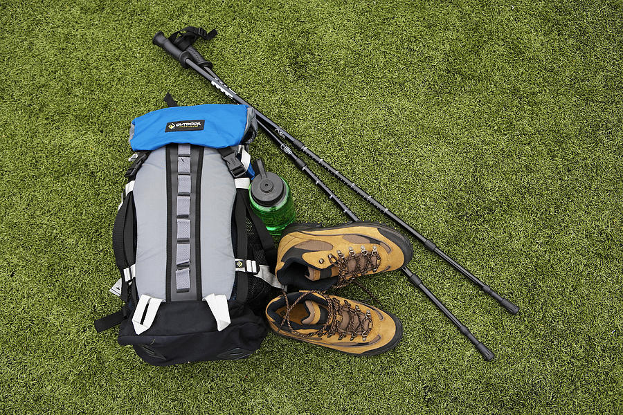 Backpack, hiking boots, water bottle and hiking pole on turf Photograph by Thomas Northcut