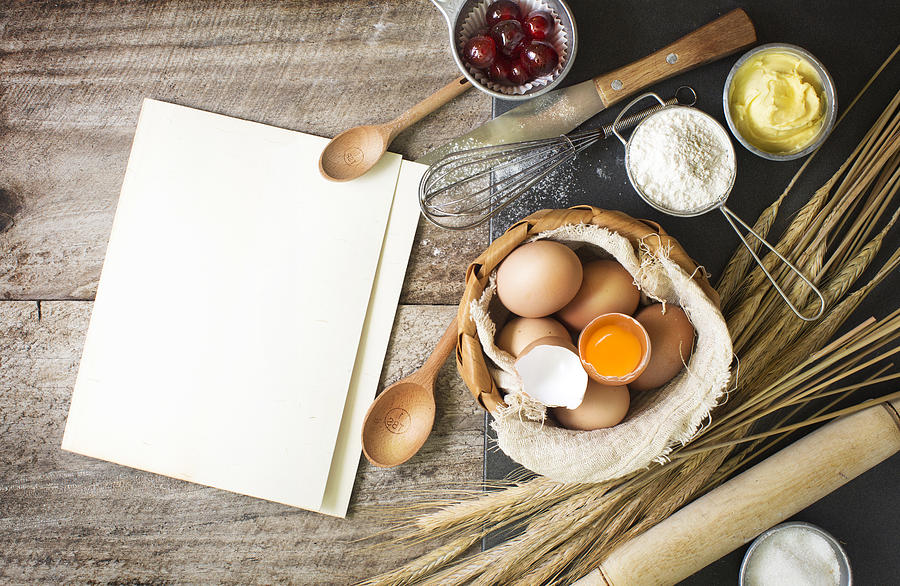 Baking ingredients and utensils on rustic wooden background. Photograph by Twomeows