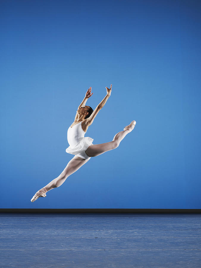Ballerina leaping on stage, side view Photograph by Thomas Barwick
