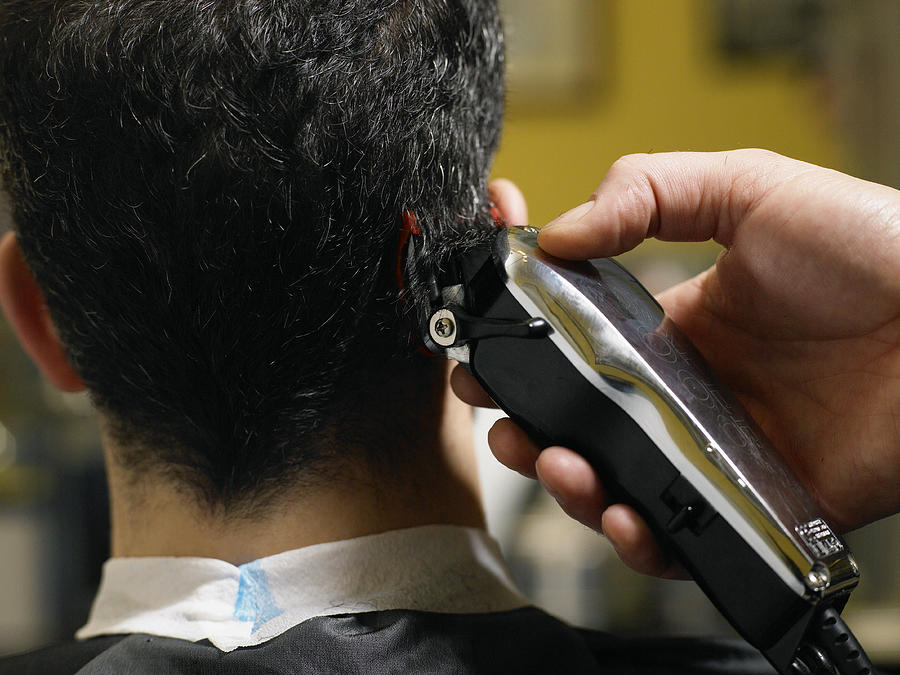 Barber cutting mans hair, close-up of electric razor, rear view Photograph by Michael Blann