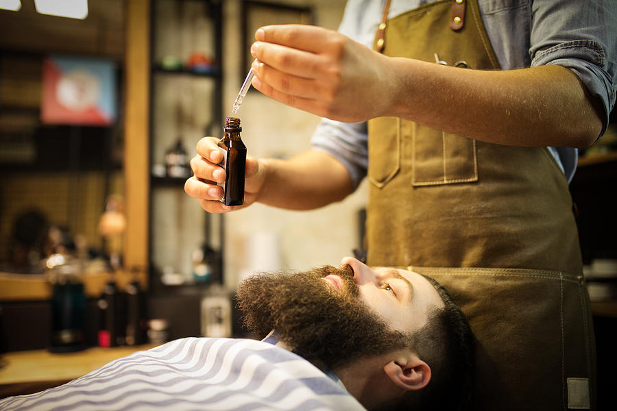 Barber putting beard oil to client Photograph by M_a_y_a