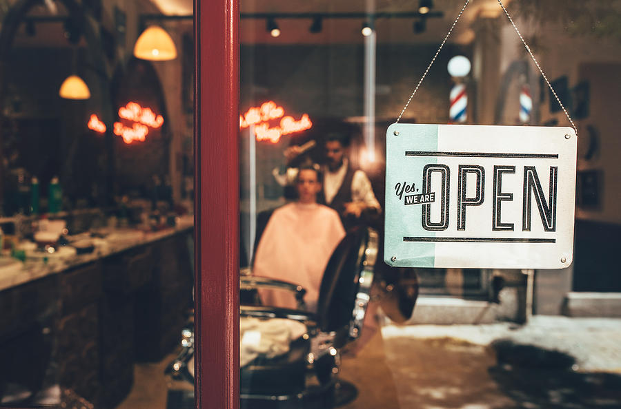 Barber shop window with open sign and barber working indoors Photograph by Wundervisuals