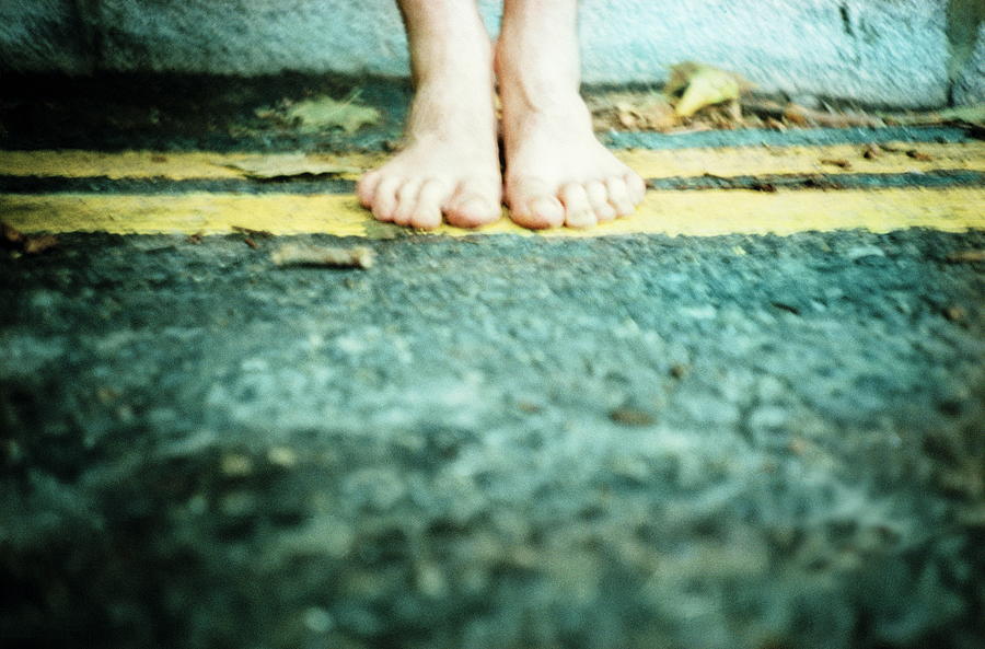 Bare-footed man on yellow lines at side of road Photograph by Anthony Marsland