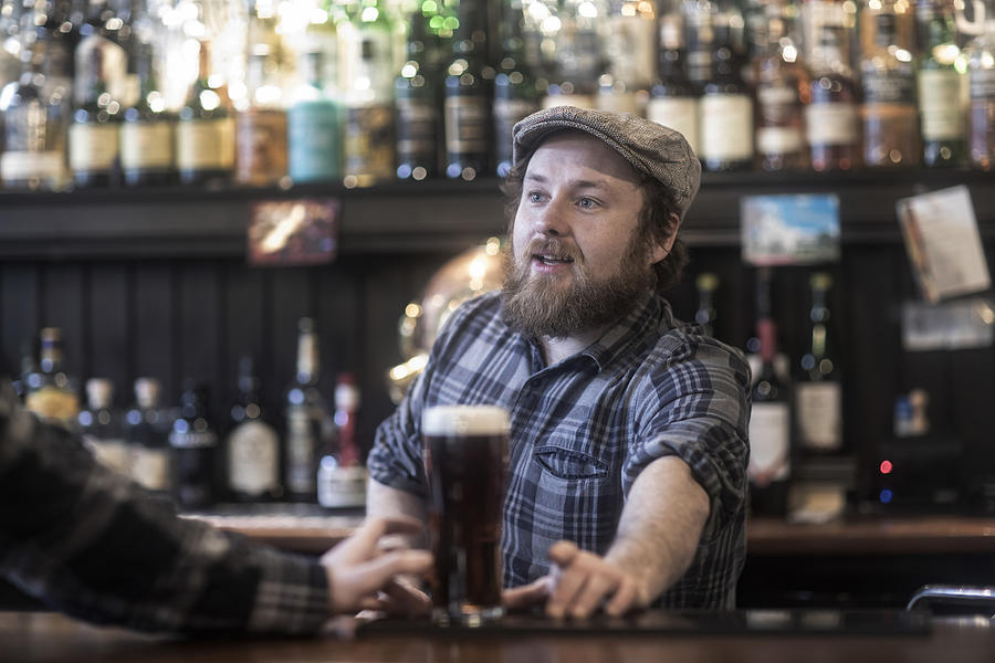 Barman serving beer to customer at bar in traditional Irish public house Photograph by Sigrid Gombert
