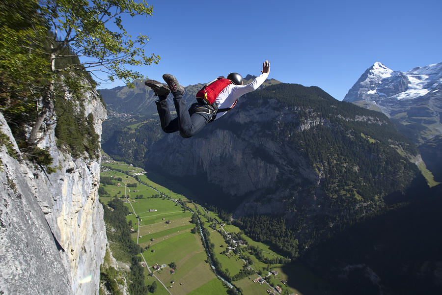BASE jumper is diving into the valley from a cliff Photograph by Oliver Furrer