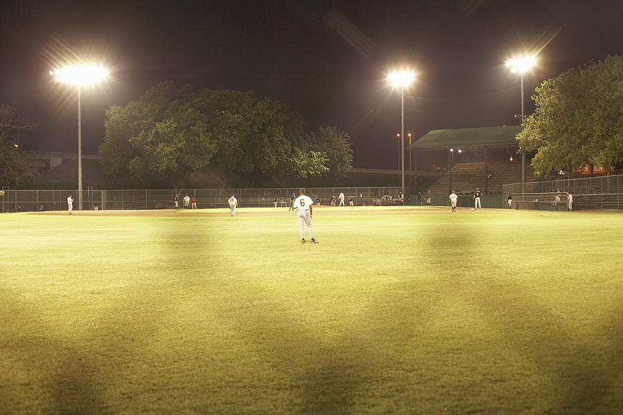 Baseball game under artificial lightning through chainlink fence Photograph by Siri Stafford