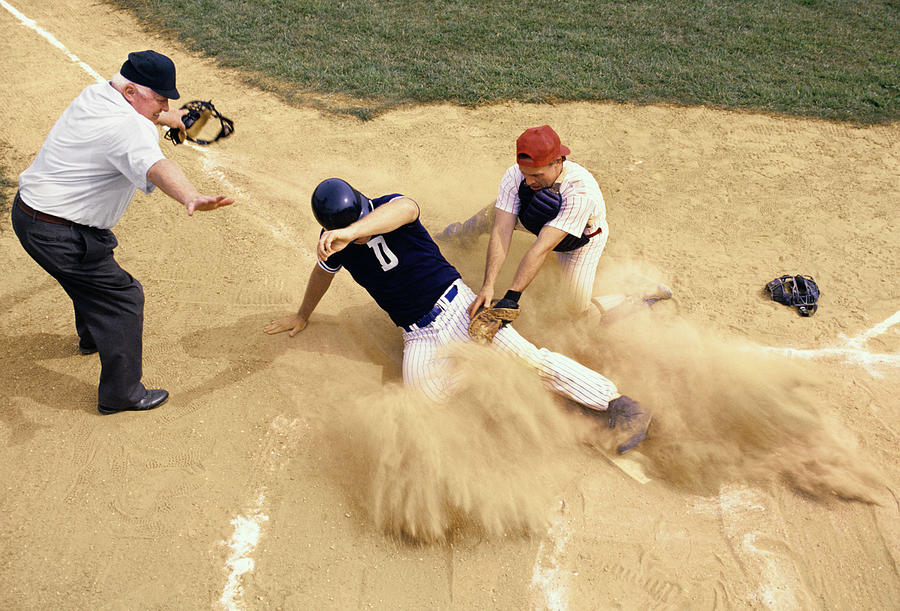 Baseball player sliding into home plate Photograph by Jupiterimages