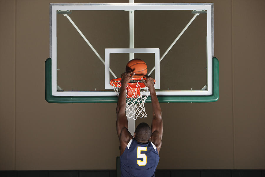 Basketball player making a basket Photograph by PhotoAlto/Sandro Di Carlo Darsa