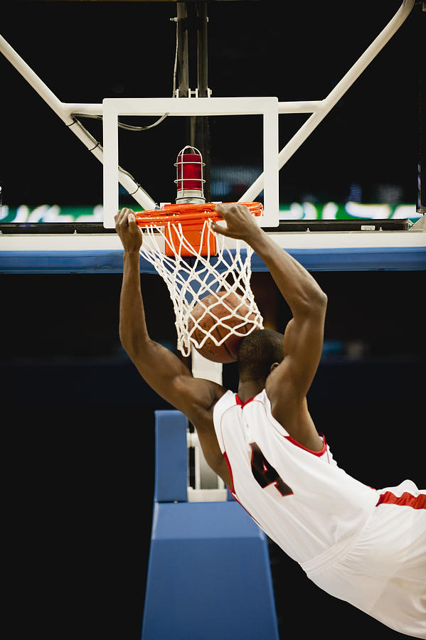 Basketball slam dunking, rear view Photograph by PhotoAlto/Odilon Dimier