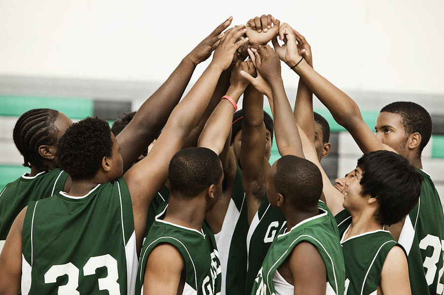 Basketball team with arms raised in huddle Photograph by Hill Street Studios